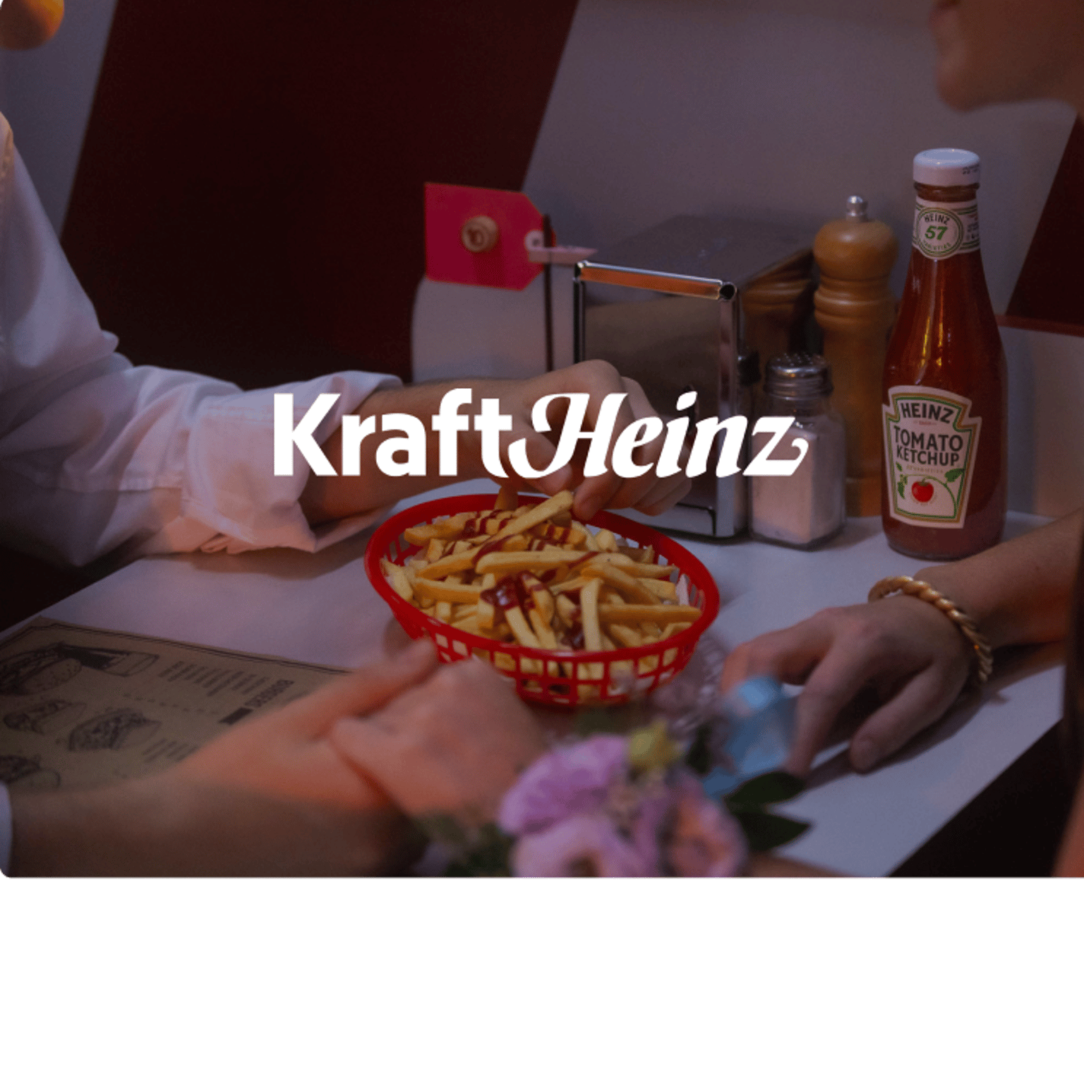 Kraft Heinz logo against a background image showing a couple holding hands while sharing a basket of fries
